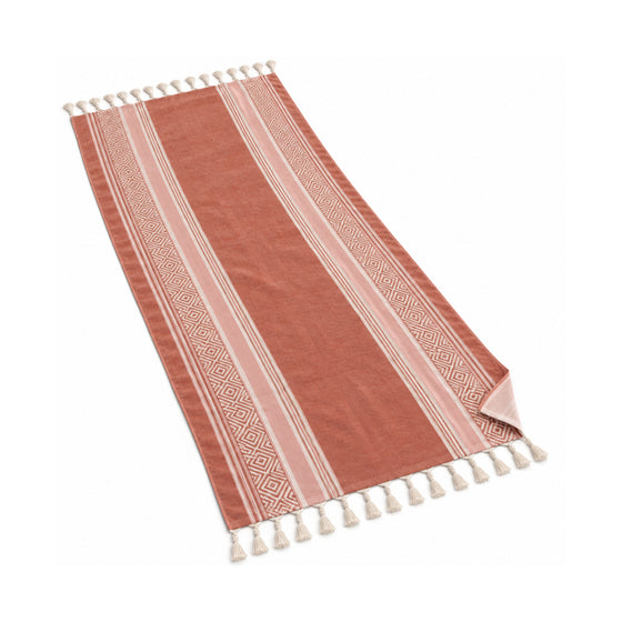 Terracotta fringed beach towel with an ornamental border pattern.