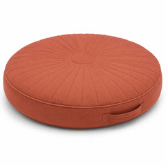 Terracotta round floor cushion with radial pleating and side handle on white background
