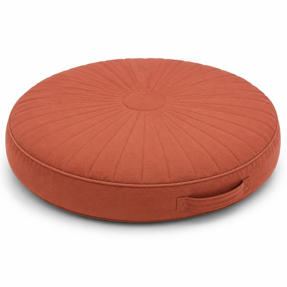 Terracotta round floor cushion with radial pleating and side handle on white background