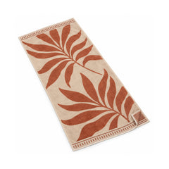 Ivory beach towel with large terracotta tropical leaf motifs.