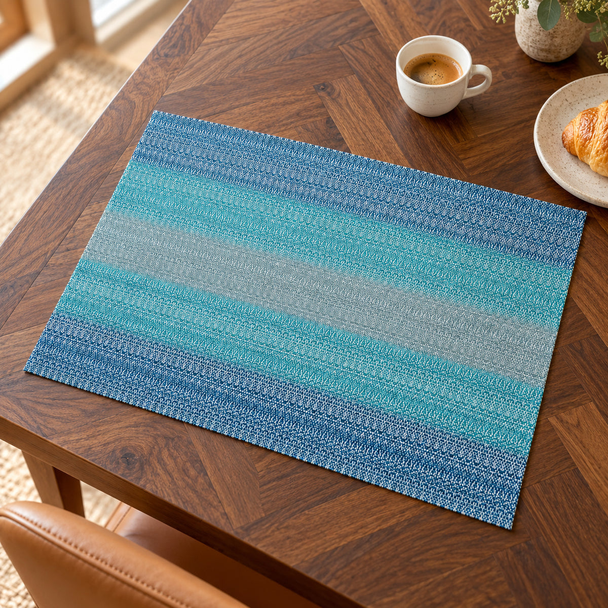 Rectangular placemat featuring horizontal stripes gradually shifting from turquoise to ocean blue with a textured woven-look surface on a walnut dining table