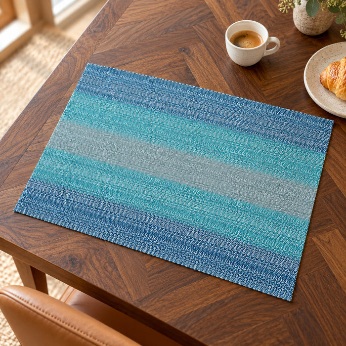 Rectangular placemat featuring horizontal stripes gradually shifting from turquoise to ocean blue with a textured woven-look surface on a walnut dining table