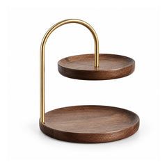 Two-tier dark walnut-tone round wooden tray stand with large lower plate, offset smaller upper plate and curved champagne-gold arch handle