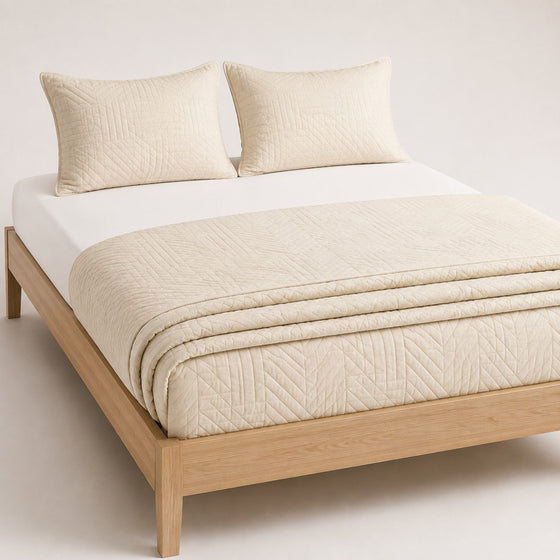Warm cream tonal geometric cotton quilt, folded with matching pillows for wholesale bedding sourcing