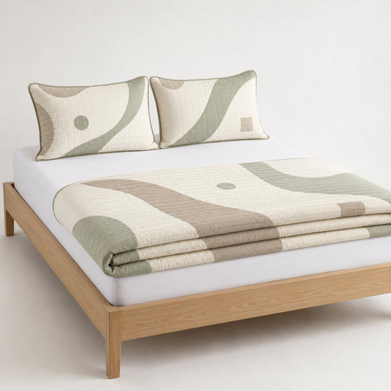 Warm ivory taupe and sage contemporary cotton quilt, folded with matching pillows for wholesale bedding sourcing