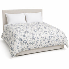 Primeval warm white blue grey delicate floral duvet cover displayed on a styled bed against a clean white studio background