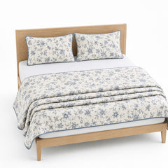 Warm white blue and grey floral cotton quilt, folded with matching pillows for wholesale bedding sourcing