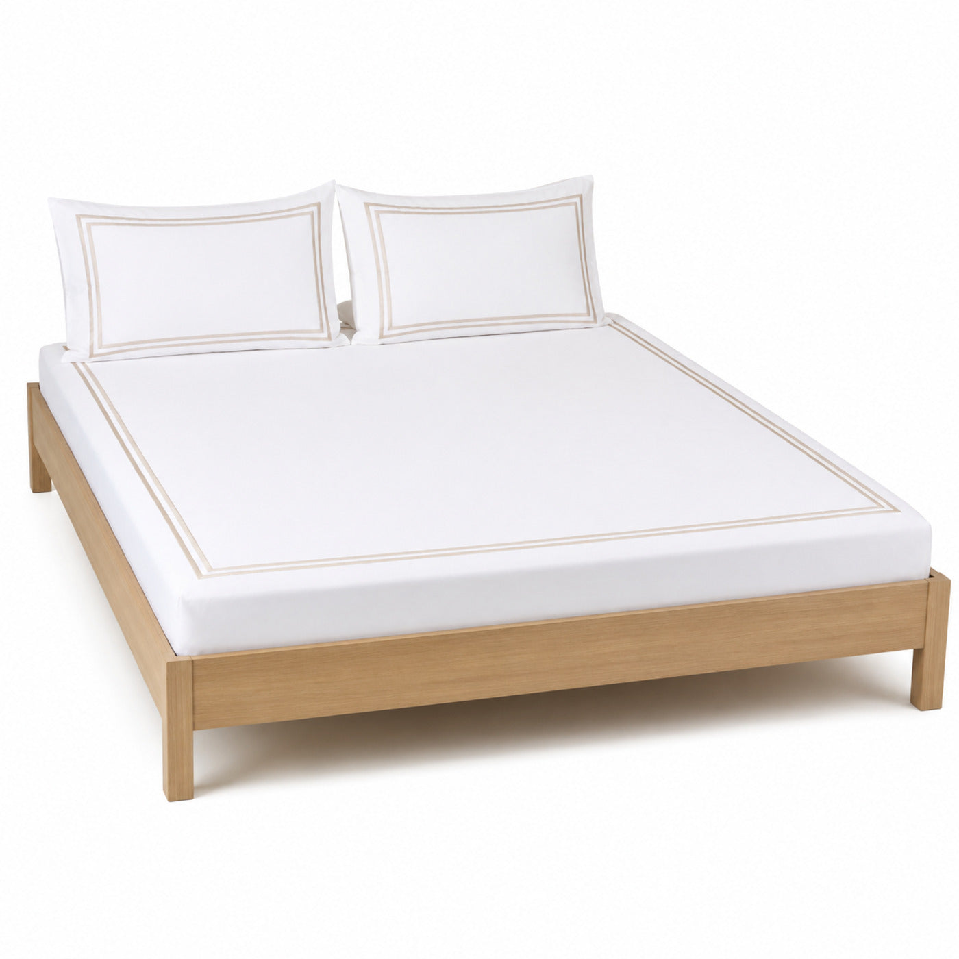 White bed sheet set with beige hotel-style border and matching pillowcases on a wooden bed