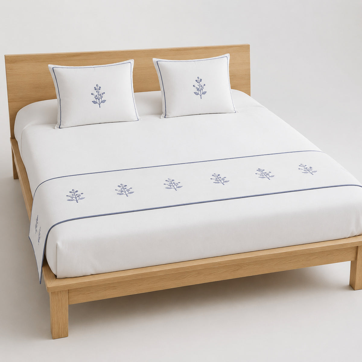 White and soft blue embroidered floral bed runner styled on white bedding for wholesale hotel and private-label sourcing