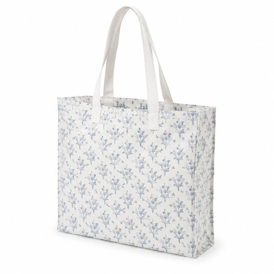 White tote bag with delicate dusty blue floral print and white handles on a white background.