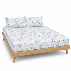 White and dusty blue floral trail bed sheet set with matching pillowcases on a wooden bed