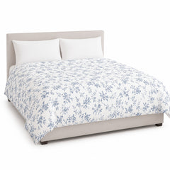 Primeval white dusty blue floral vine duvet cover displayed on a styled bed against a clean white studio background